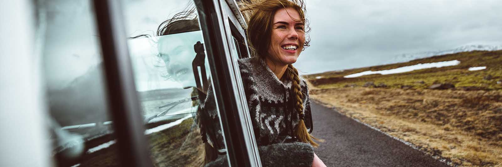 Young woman sticking her head out of a Jeep on a tour