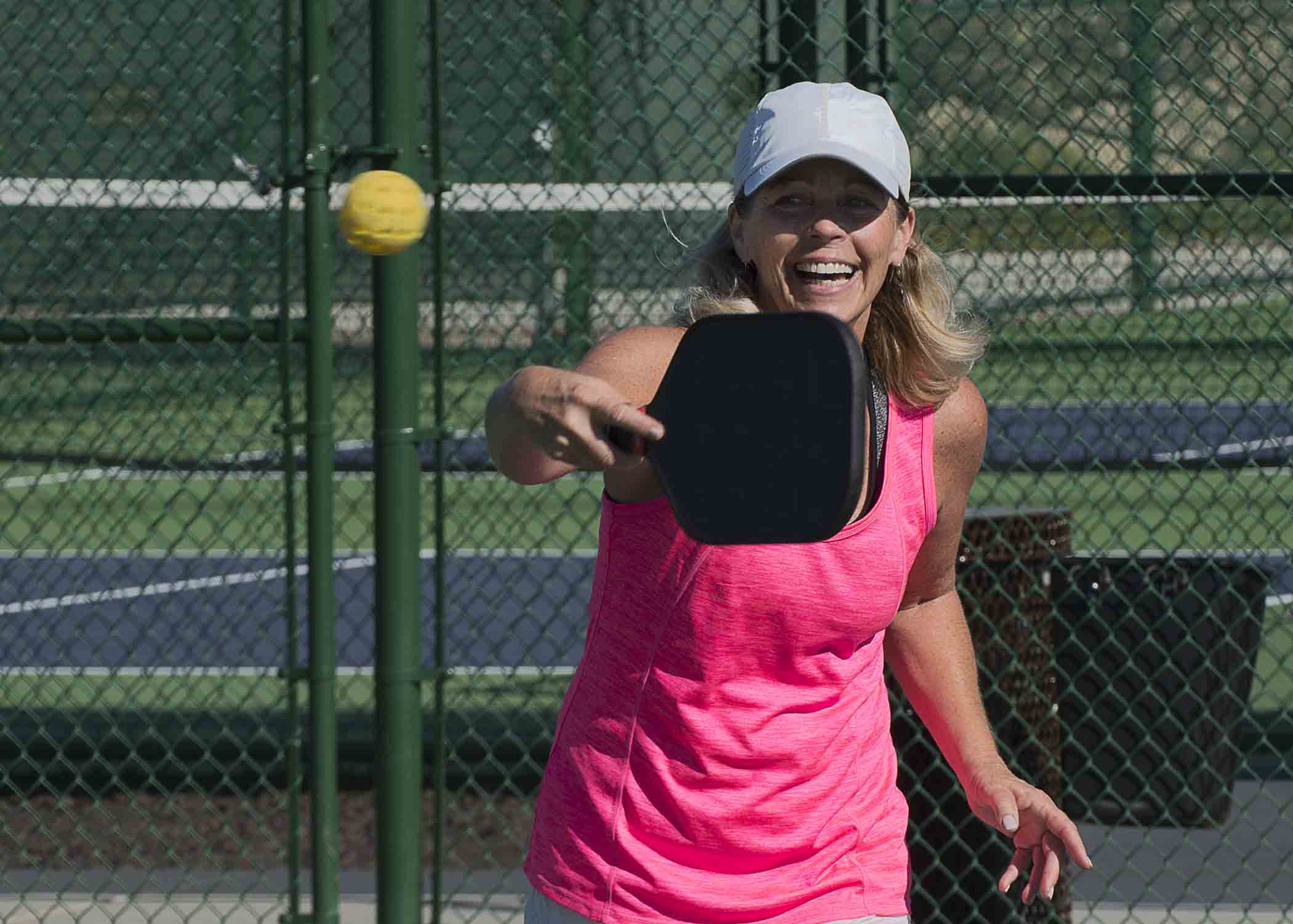 Woman in pink shirt playing pickleball